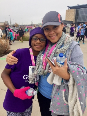 A Black mother and daughter pose together wearing race medals.