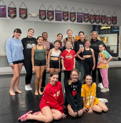 A group of several teenage girls pose together in a dance studio.