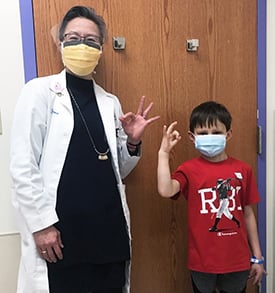 Dr. Christine Cheng with Dillan Mecham giving the "OK" sign with their hands and fingers.