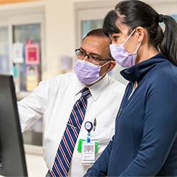 Vimal Chadha, MD talks with a colleague while looking at a computer screen