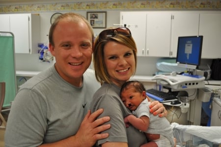 Parents pose with their infant baby, who has a cleft lip.