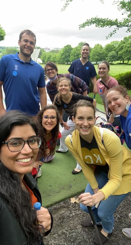 Several young adults pose together on a miniature golf course.