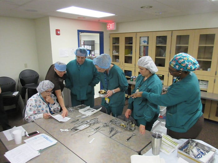 Six Children's Mercy providers gathered around a table looking at a paper as part of a Rapid Performance Review.