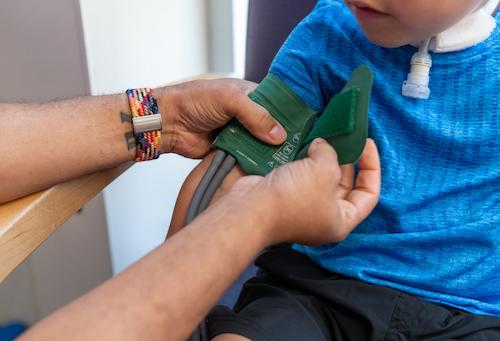 close up of a nurse wrapping green blood pressure cup around patient arm 