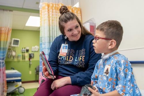 Child life specialist showing patient photos of OR room via an iPad 