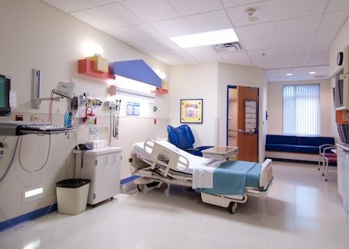 view of empty inpatient room that includes: bed extra seating for visitors and computer for staff use. 