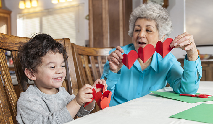 Young boy and grandma cutting heart paper garlands